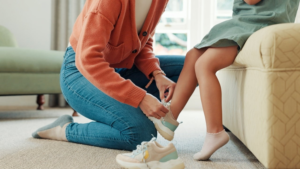 mom putting on daughter's sneakers