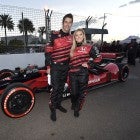 Arie Luyendyk Jr. and Lauren Burnham pose with Honda race car