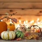 Autumn pumpkins, gourds and holiday decor arranged against an old wood background with glowing Christmas lights. Very shallow depth of field for effect.