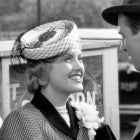 Virginia Patton in 'It's a Wonderful Life' smiling at her on-screen brother-in-law, played by James Stewart. She wears a fascinator hat and floral pin on her shoulder.