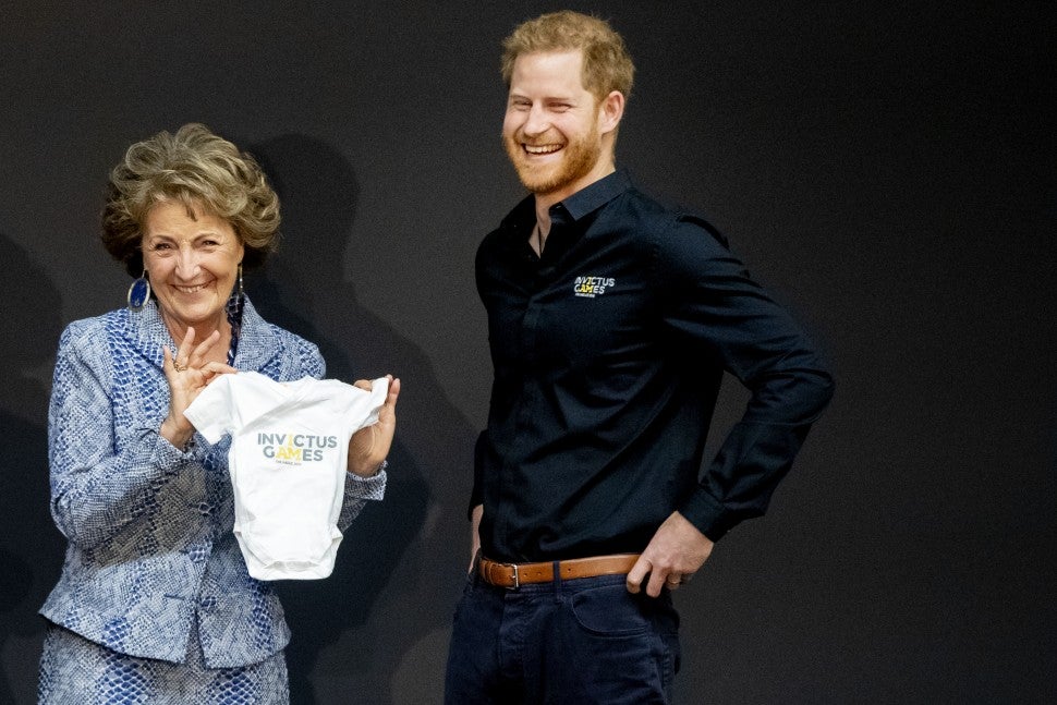 Prince Harry is presented with an Invictus Games onesie for his newborn son Archie by Princess Margriet of The Netherlands during the launch of the Invictus Games on May 9, 2019