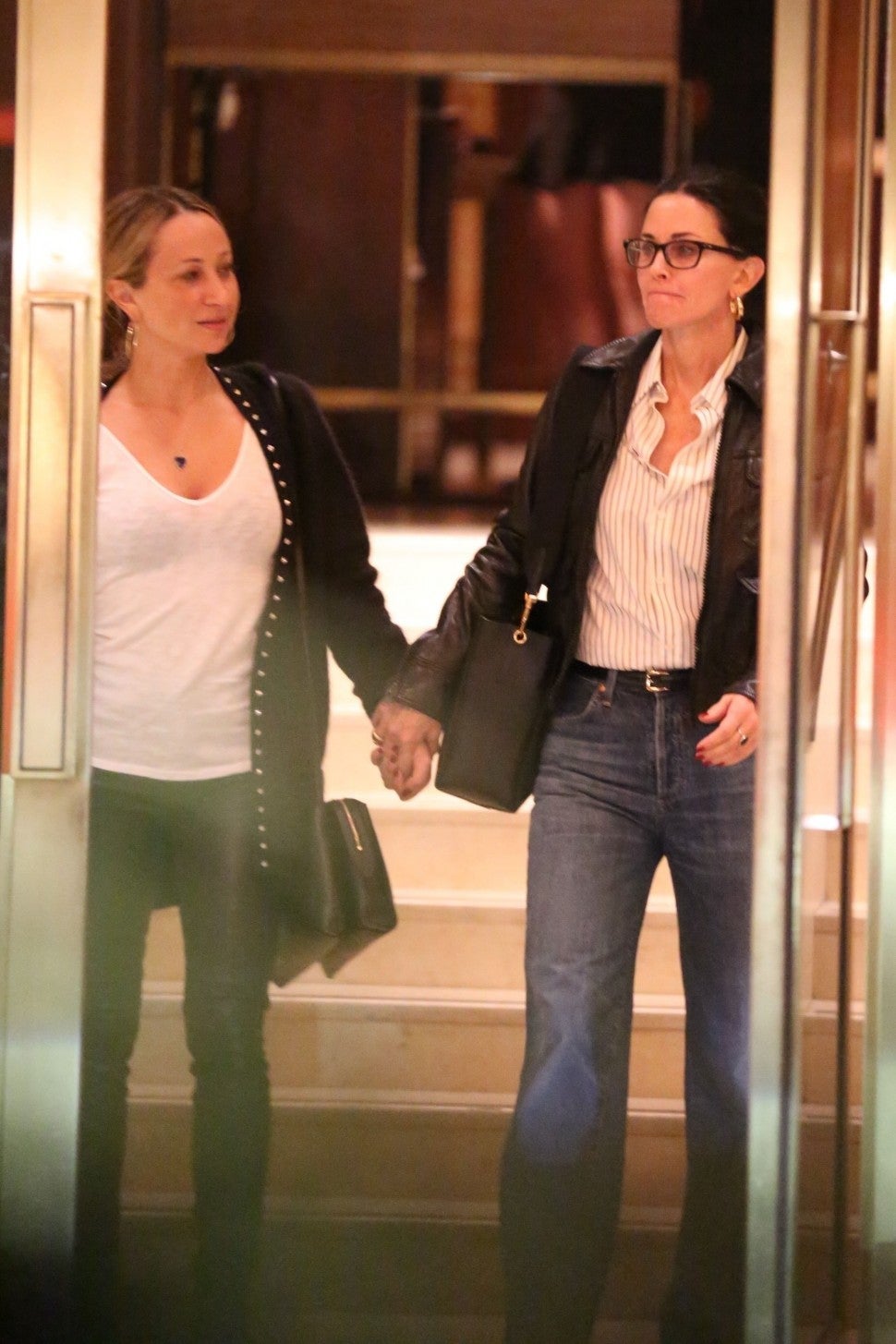 Courteney Cox and Jennifer Meyer hold hands as they leave Jennifer Aniston's 51st birthday party at the Sunset Tower Hotel in West Hollywood.