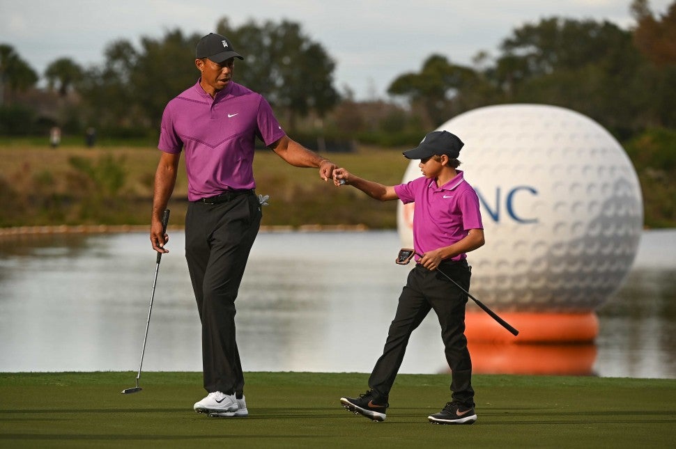 Tiger Woods fist bumps his son Charlie Woods after making a putt on the 16th green during the first round of the PGA TOUR Champions PNC Championship at Ritz-Carlton Golf Club on December 19, 2020 in Orlando, Florida. 