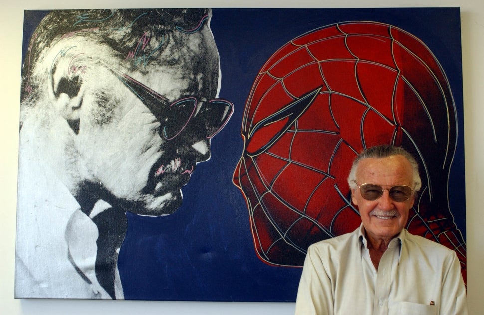 Stan Lee stands in front of mural depicting him and Spider-Man staring each other down.