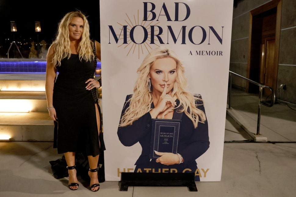 Heather Gay poses with a giant mockup of her book cover on The Real Housewives of Salt Lake City