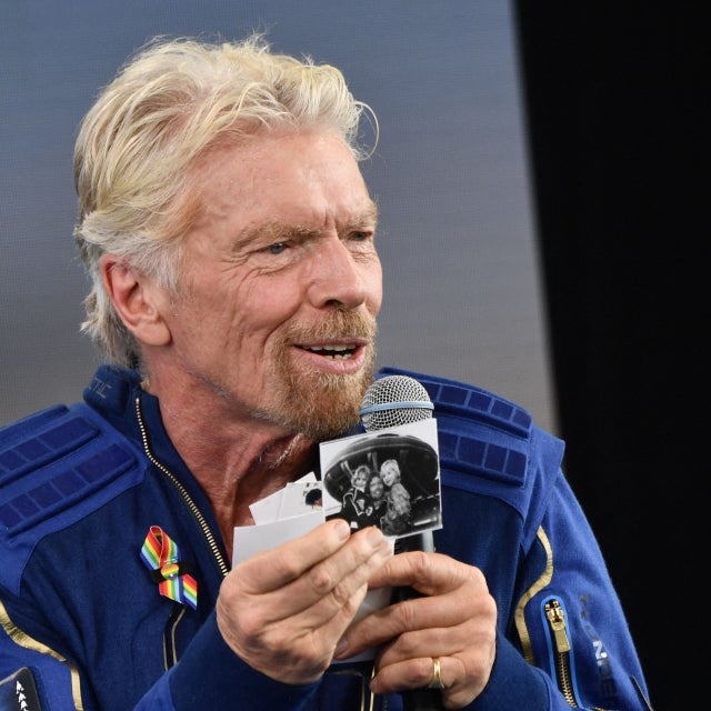 Sir Richard Branson holds up photos that he brought with him into space, as he speaks after flying into space aboard a Virgin Galactic vessel, a voyage he described as the "experience of a lifetime" -- and one he hopes will usher in an era of lucrative space tourism at Spaceport America, near Truth and Consequences, New Mexico on July 11, 2021
