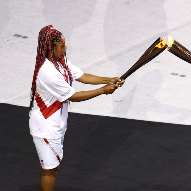 Naomi Osaka of Team Japan is handed the Olympic torch during the Opening Ceremony