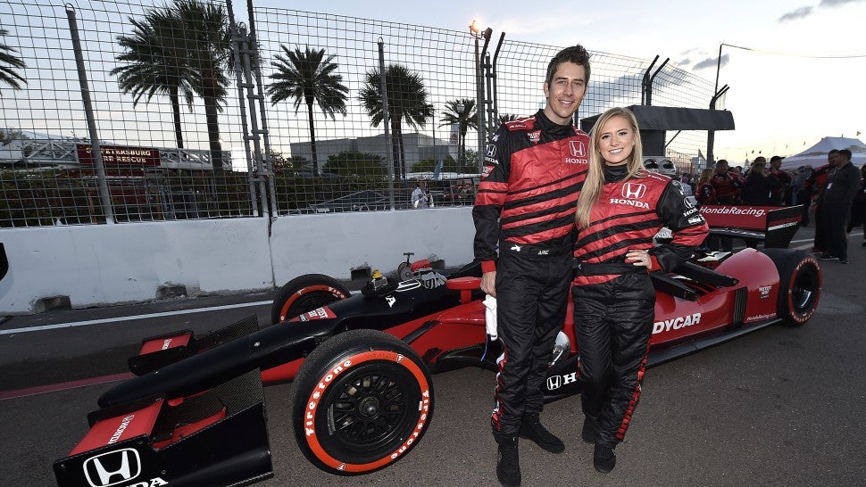Arie Luyendyk Jr. and Lauren Burnham pose with Honda race car