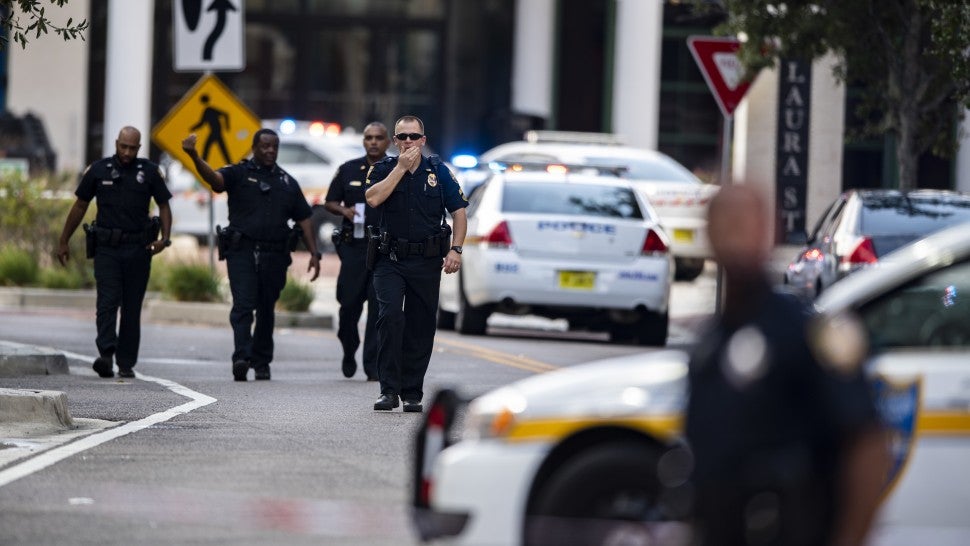 Police gather after an active shooter was reported at the Jacksonville Landing in Jacksonville, Fla., Sunday, Aug. 26, 2018. A gunman opened fire Sunday during an online video game tournament that was being livestreamed from a Florida mall, killing multiple people and sending many others to hospitals.