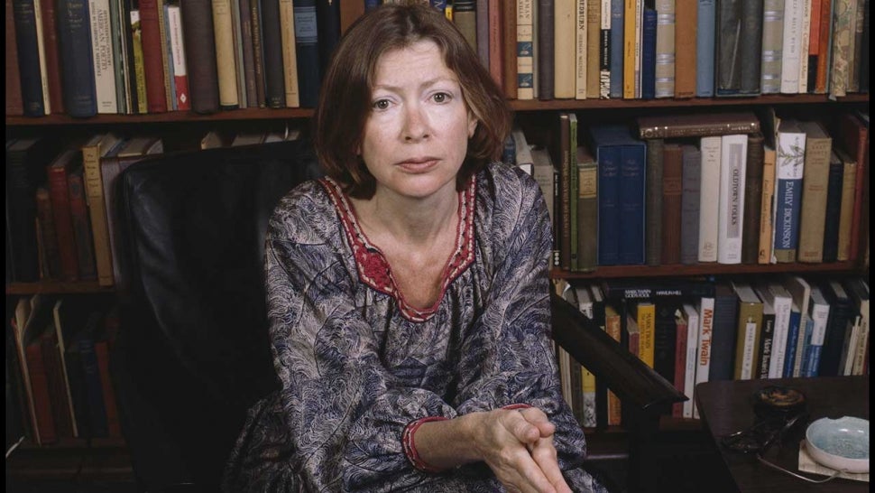 Portrait of American author Joan Didion as she sits in a chair in front of a bookshelf, Berkeley, California, April 1981. 