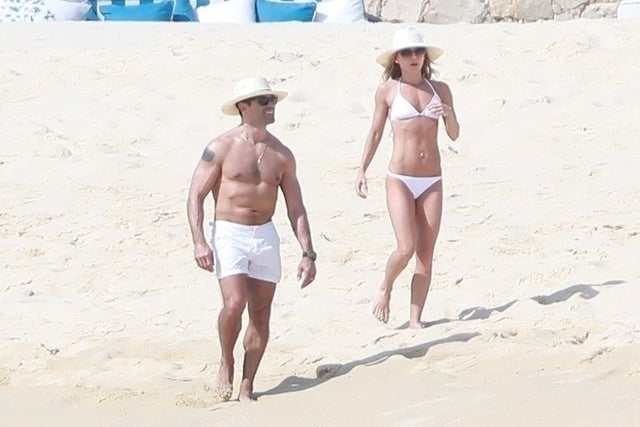 Kelly Ripa showed off her rock hard body in a tiny white bikini while strolling along the sand with hubby Mark Consuelos.