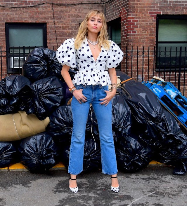 Miley Cyrus poses in front of garbage bags in Brooklyn