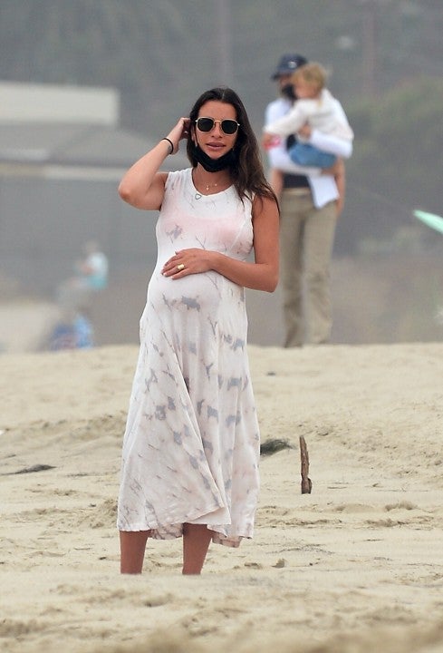 Lea Michele cradles baby bump at beach